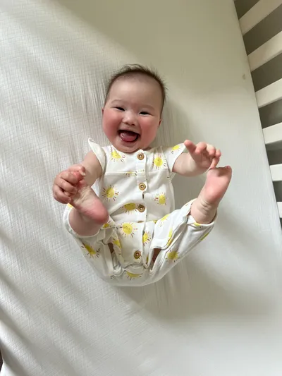 Olivia grabs her feet with a huge smile in her crib